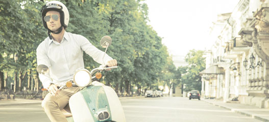 chico en ciclomotor circulando por una ciudad